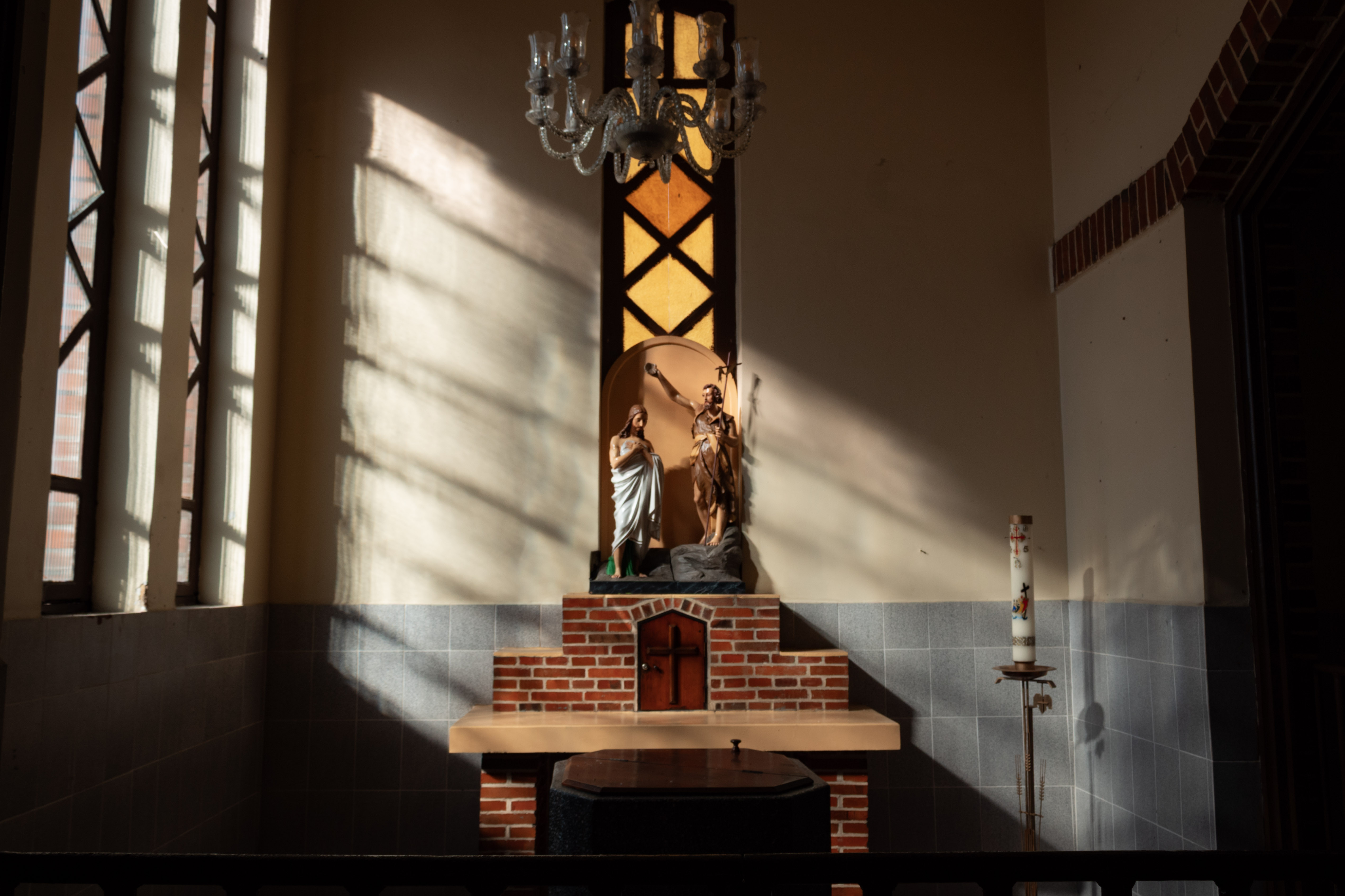 Statues of the baptism of Jesus lit by afternoon sun on a side altar