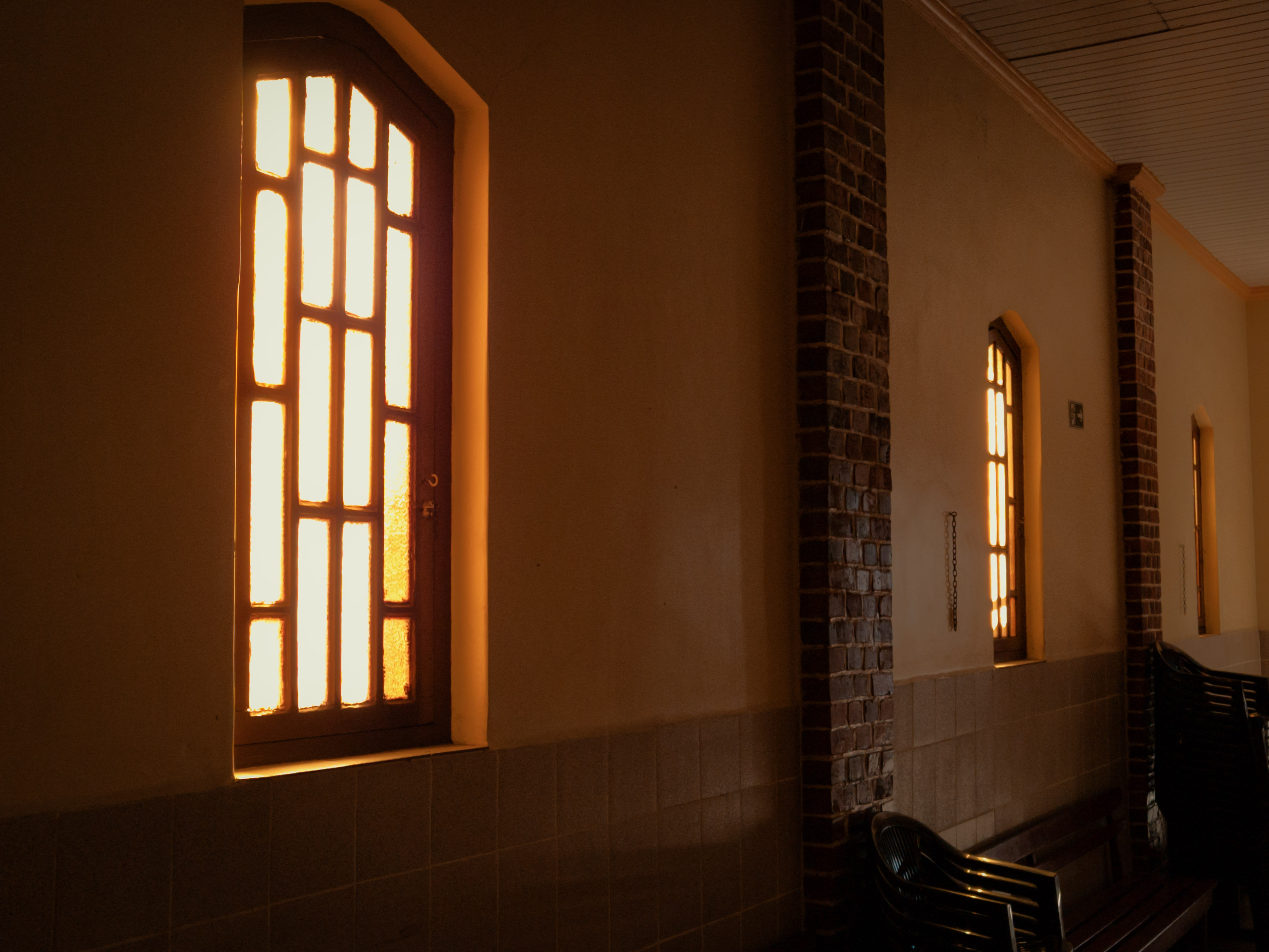 Chapel side aisle with wooden pews and sunlit arched windows